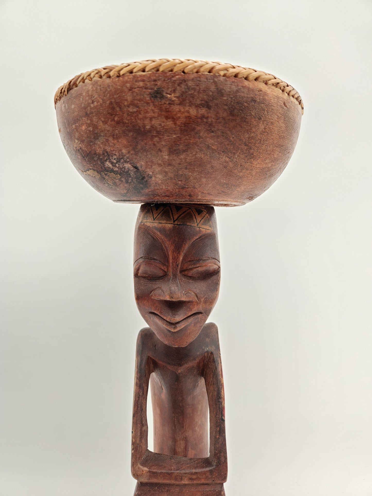 Primitive wood carving of a woman with a cup for head