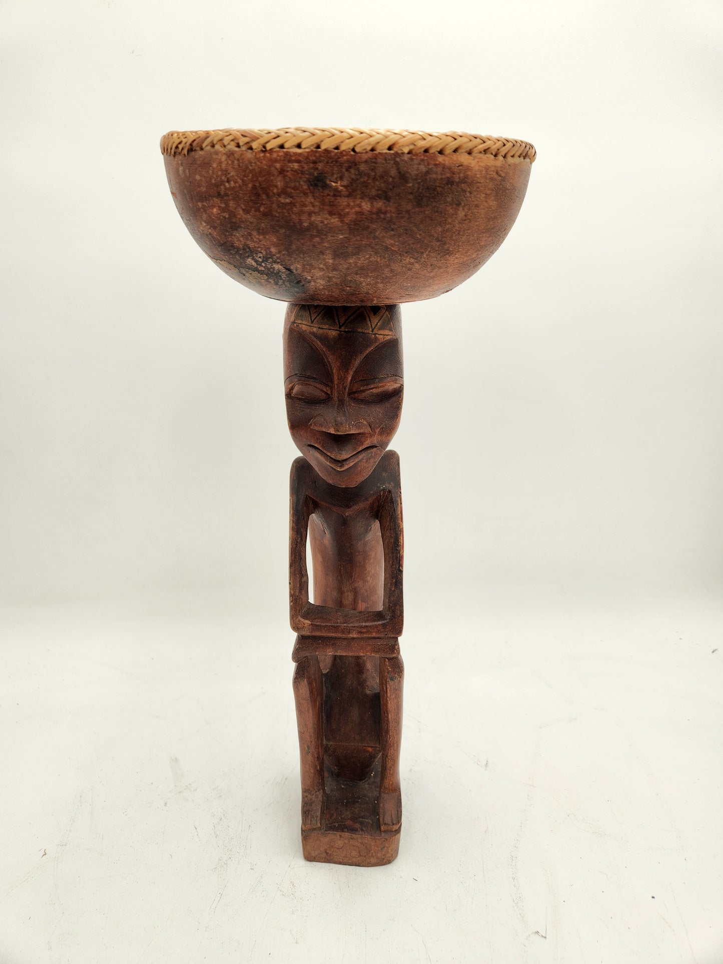 Primitive wood carving of a woman with a cup for head
